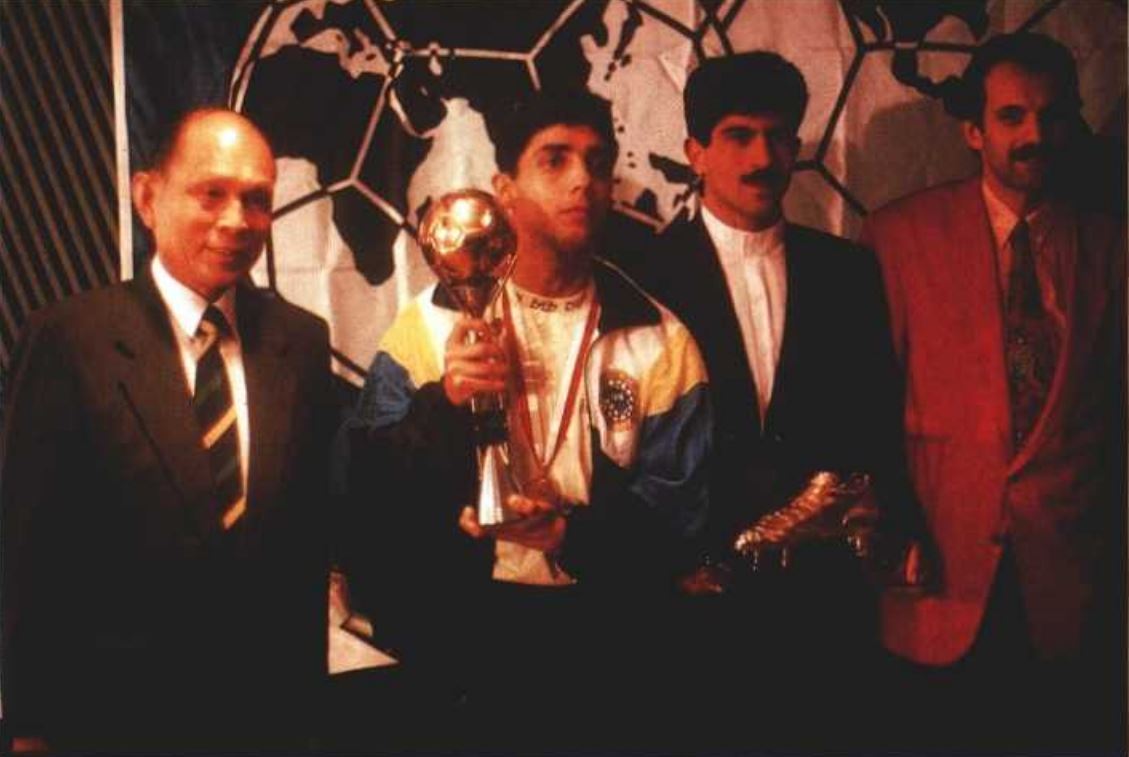 時任國際足協執行委員會成員霍英東向巴西的佐真奴（左二）及伊朗球員薩義德（Rajabi Shirazi Saeid，左三）分別頒發金球獎及金靴獎。右旁為港隊教練靴文斯。（圖片來源：FIFA）