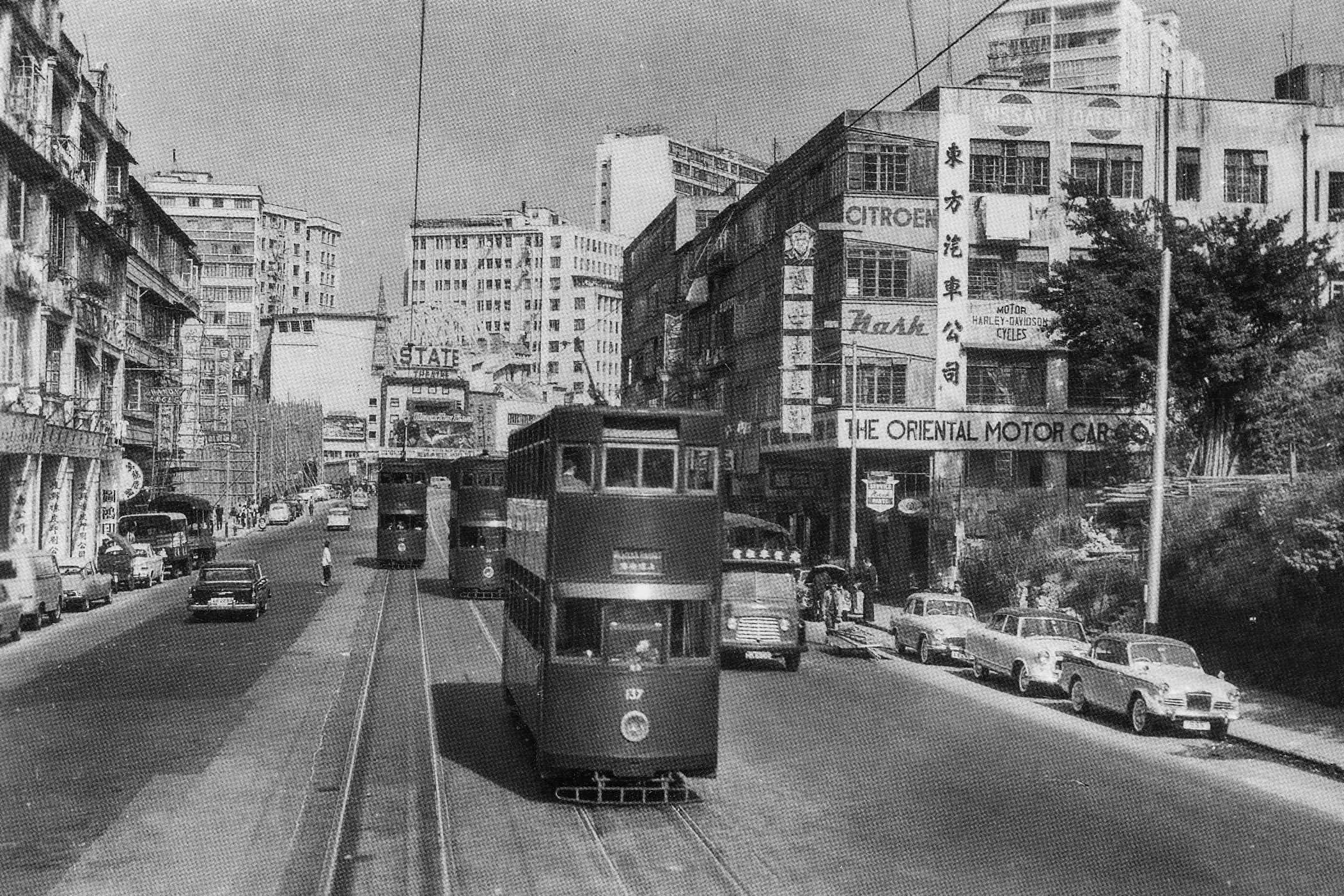 約1960年由炮台山道口向東望英皇道，中間為皇都戲院（前身為璇宮戲院）。為了興建住宅大樓南天大廈，左邊的英皇道與電廠街之間正進行鏟平小山的工程。（圖片來源：鄭寶鴻提供）