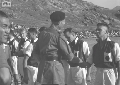 1945年11月１日，金冕多對華聯的比賽開始前，駐港英軍司令菲士廷少將（Francis Festing）與雙方球員握手。左旁為當時華聯隊長李惠堂。（圖片來源：Imperial War Museum）